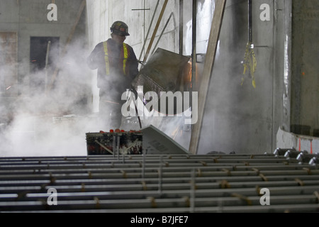 Worker cutting opening in concrete wall; Canada, Ontario, Hamilton (Composting Facility) Stock Photo