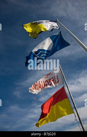 Lifeguard flags and Blue Flag water quality award flying over the beach in Port Eynon Gower Stock Photo