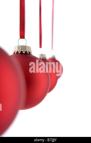 Line Of Red Christmas Decorations Hanging Against White Background Stock Photo