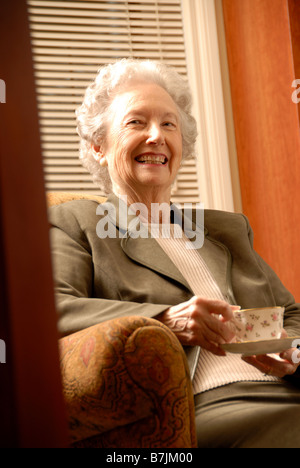 Senior Woman in Library with Tea; Canada, Saskatchewan, Regina Stock Photo