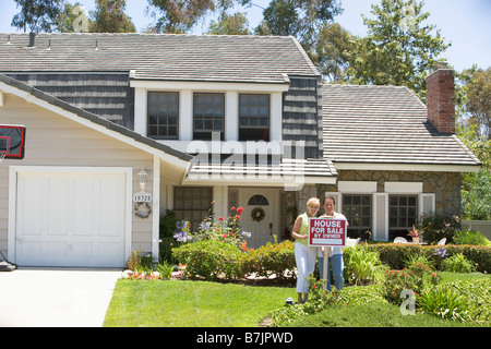 Couple Standing Outside House With Real Estate Sign Stock Photo - Alamy