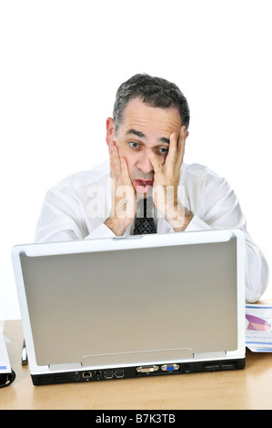Stressed businessman sitting at his desk isolated on white background Stock Photo