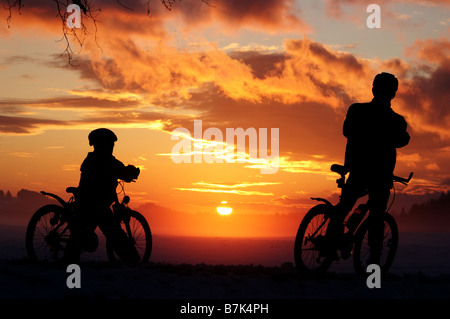 Father and son riding through misty sunset Stock Photo
