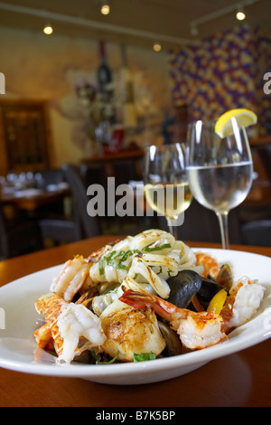 Seafood dish with white wine and glass of water in restaurant setting Stock Photo