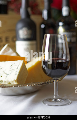 Glass of red wine with bricks of blue, cheddar, parmesan, and brie cheese in a silver dish Stock Photo