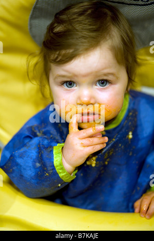 A baby girl ponders her next spoonful during feeding time Stock Photo