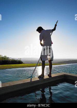 Man cleaning swimming pool Stock Photo