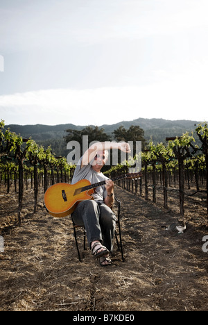 Musician sitting in vineyard with guitar, lifestyle portrait. Stock Photo