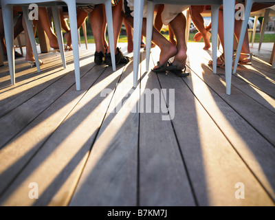 Many legs under table casting shadows Stock Photo