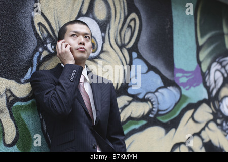 Businessman on Cellphone Leaning against the Wall Stock Photo