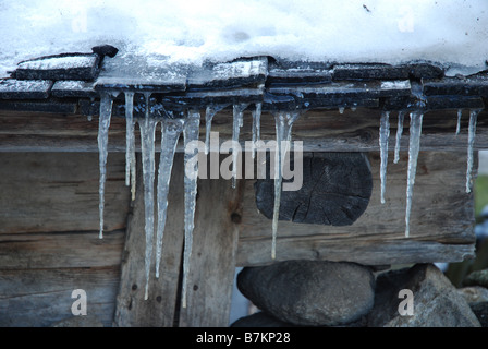 ice hanging from roof of old fashioned Austrian shed in winter Stock Photo