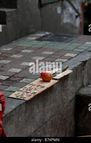 Knife and apple on the wall of a very dirty local market full of chicken blood durring Bird flu outbreak in China Cross conamina Stock Photo