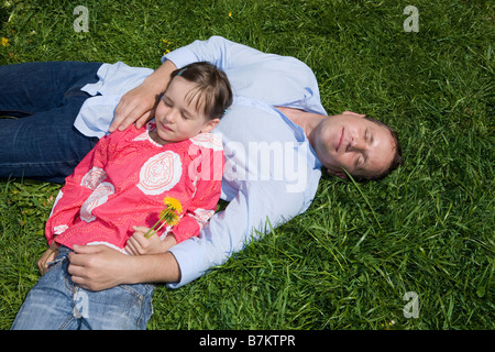 Father and daughter (6-7) relaxing in the meadow, elevated view Stock Photo