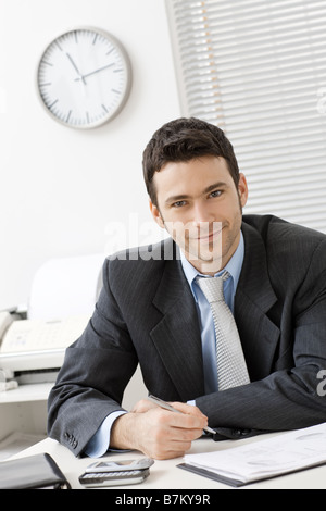 Happy young businessman working at desk at office smiling Stock Photo