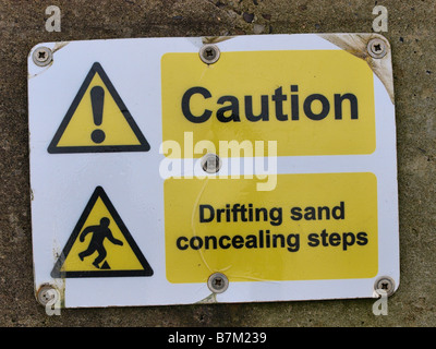 CAUTION SIGN  ON SEA WALL WARNING OF  DRIFTING SAND AT ECCLES NORFOLK EAST ANGLIA ENGLAND UK Stock Photo