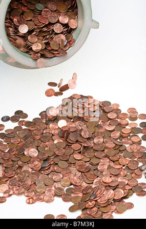 A bowl full of pennies spilled out onto a white background. Stock Photo