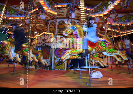 Child rides illuminated traditional carousel fairground ride at Winter Wonderland, Hyde Park, London, UK Stock Photo
