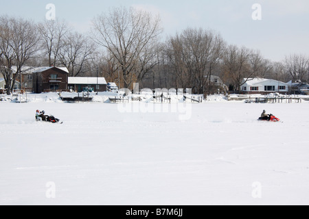 A young people ride on a snowmobile on a frozen white Lake in Ohio USA US lifestyle daily life all only a lot of snow from above top view hi-res Stock Photo