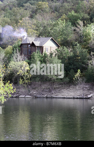 A log cabin on the cliff above a lake during the Fall season in Branson Missouri Stock Photo