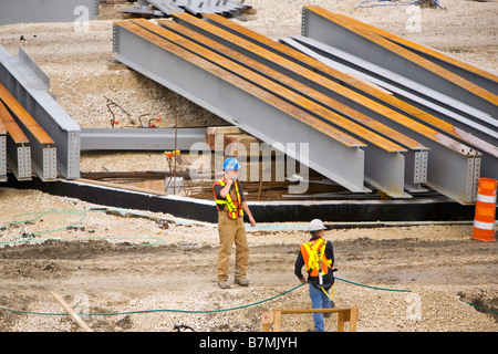 Construction workers and a row of steel girders, at a construction site. Stock Photo
