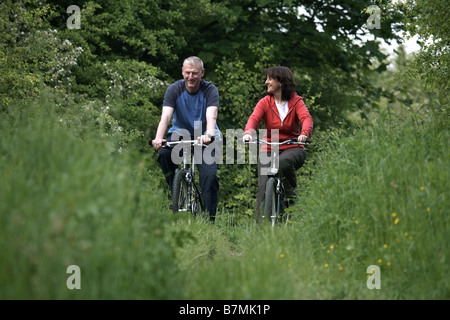 Couple cycling on the disused railway line near Market Weighton The Wolds East Yorkshire UK Stock Photo