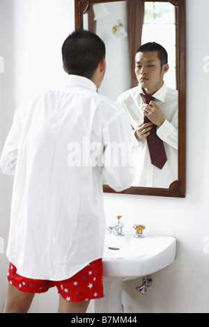 Man Adjusting His Tie in Bathroom Stock Photo