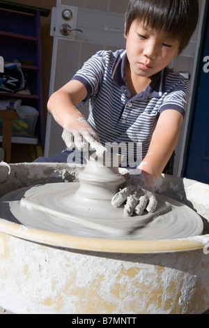 eight year old japanese boy working on a ceramic pot using a wheel Stock Photo