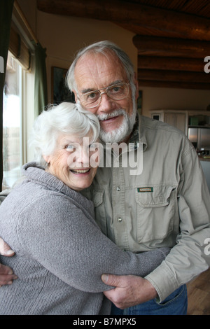 cute elderly married couple in seventies, embracing at home, smiling at camera Stock Photo