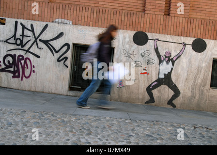 A pedestrian walks past graffiti on Via Riberi, Turin, Piedmont, Italy Stock Photo