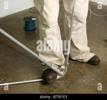 Closeup of electrician s feet as he bends pipe Work being performed by actual electrician in accordance with national code Stock Photo