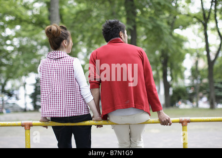 Couple Leaning on a Metal Railing in the Park Stock Photo