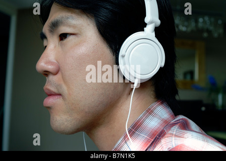 Young "Asian Man" Portrait Listening to Music on Headphones "MP3 Music Player" "I Pod" Portrait Silhouette Head Stock Photo