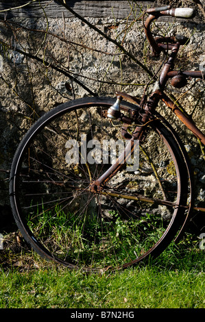 Stock photo of a very old rusty bike left leaning against a wall Stock Photo