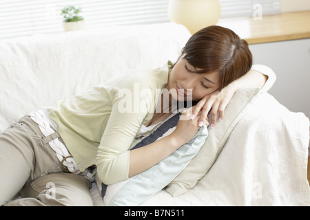 Young woman lying on sofa at home Stock Photo - Alamy