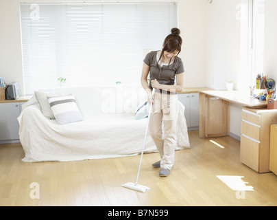 Woman Sweeping Floor in Living Room Stock Photo
