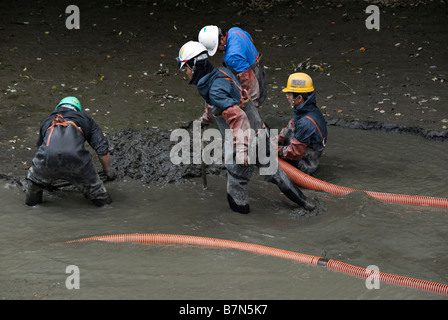 Okayama, Japan. Workers in the garden of Koraku-en pumping out mud while cleaning a pond Stock Photo