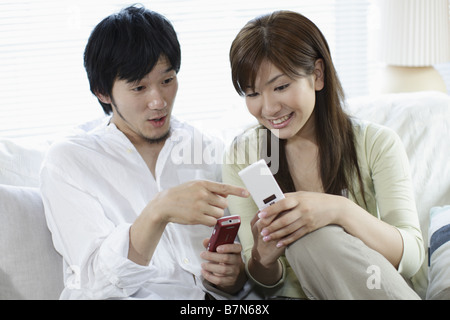 Couple Holding Cell-Phone and Looking at It Stock Photo