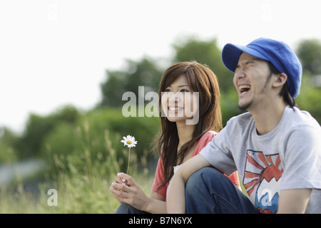 Smiling Couple Sitting on Grass Stock Photo