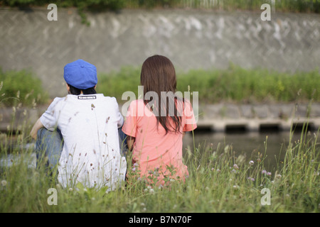 Couple Sitting on Grass, rear view Stock Photo