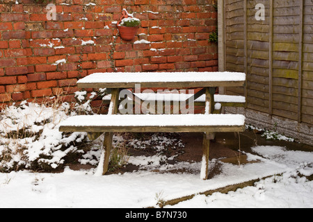 Garden wooden table or bench covered in winter in the uk snow Stock Photo