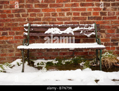 Old garden seat bench covered in snow in an English garden in winter Stock Photo