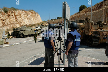 TV news crew wearing protective flak jacket filming Israeli troops mass at the northern Israel Lebanon border Stock Photo