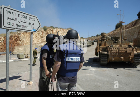 TV news crew wearing helmet and protective flak jacket marked 'TV' filming Israeli troops mass at the northern Israel Lebanon border Stock Photo