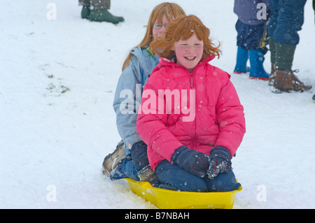 Two children Girls teenagers on A Sled sledge sledging Snow Stock Photo