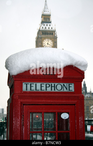 Red phone box covered in snow with big Ben behind Stock Photo