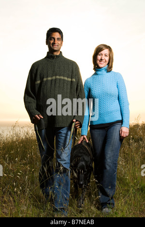 couple walking dog outdoors at sunset in california on hill Stock Photo