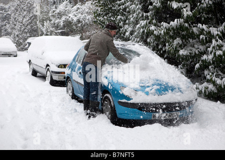 A man cleans snow from his car in Muswell Hill north London on the 2nd of February 2009 Stock Photo