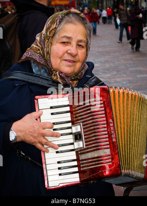 Woman busker playing an accordion for money in Buchanan Street Glasgow Scotland Stock Photo