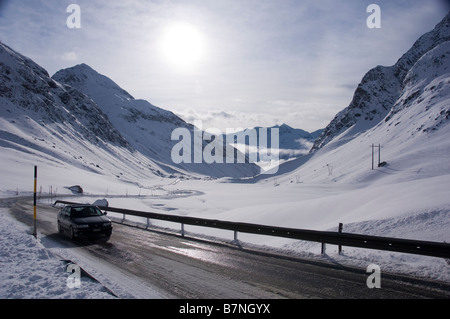 Passing car on the snow covered Julier pass near the highest point. Swiss Alps, Graubunden. Stock Photo
