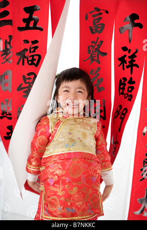 Girl in Chinese traditional clothes with red envelopes standing Calligraphy in the background Stock Photo